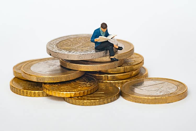 Imagen representativa de un préstamo bancario donde se muestra a un hombre sentado en unas monedas.