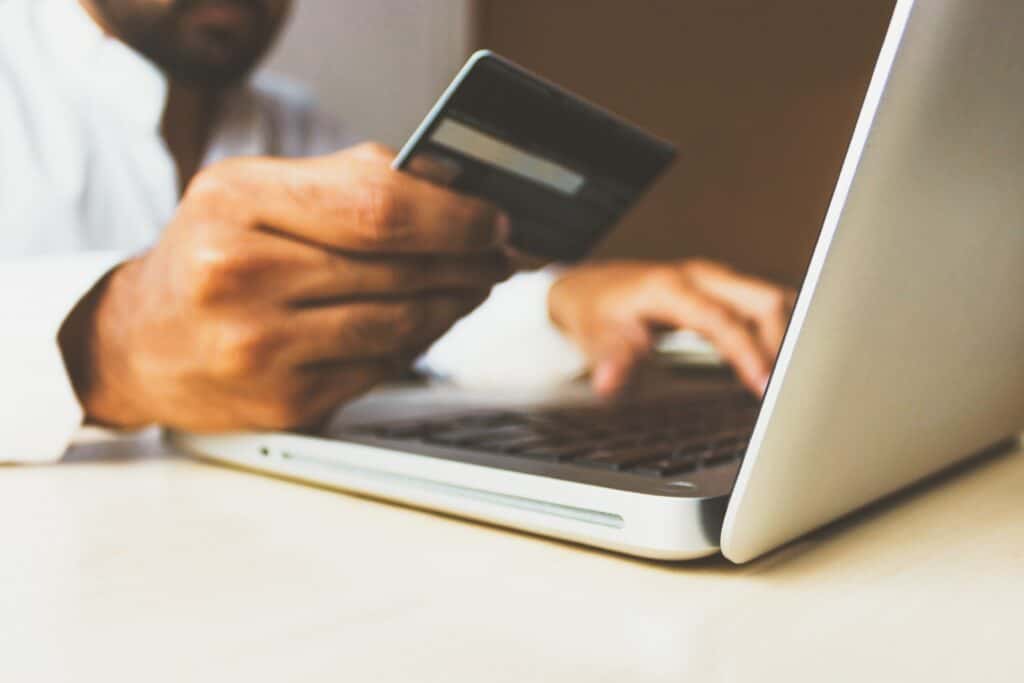persona frente a un computador con una tarjeta de crédito, la cual se recomienda usar con cuidado.