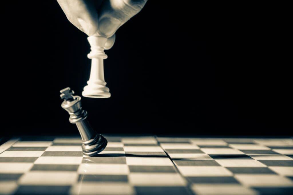 ficha blanca de ajedrez derrotando a la negra, en representación al pensamiento estratégico.
