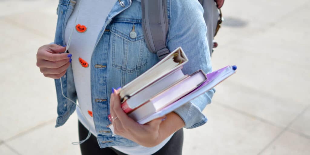 Estudiante de Administración de Negocios Internacionales con sus auriculares, libros y mochila.