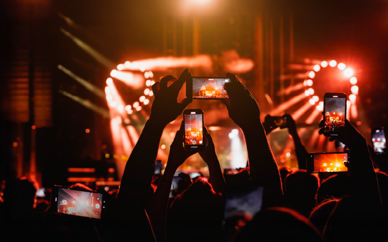 Fanáticos capturando momentos con sus celulares durante un concierto, símbolo de la experiencia digital post evento.